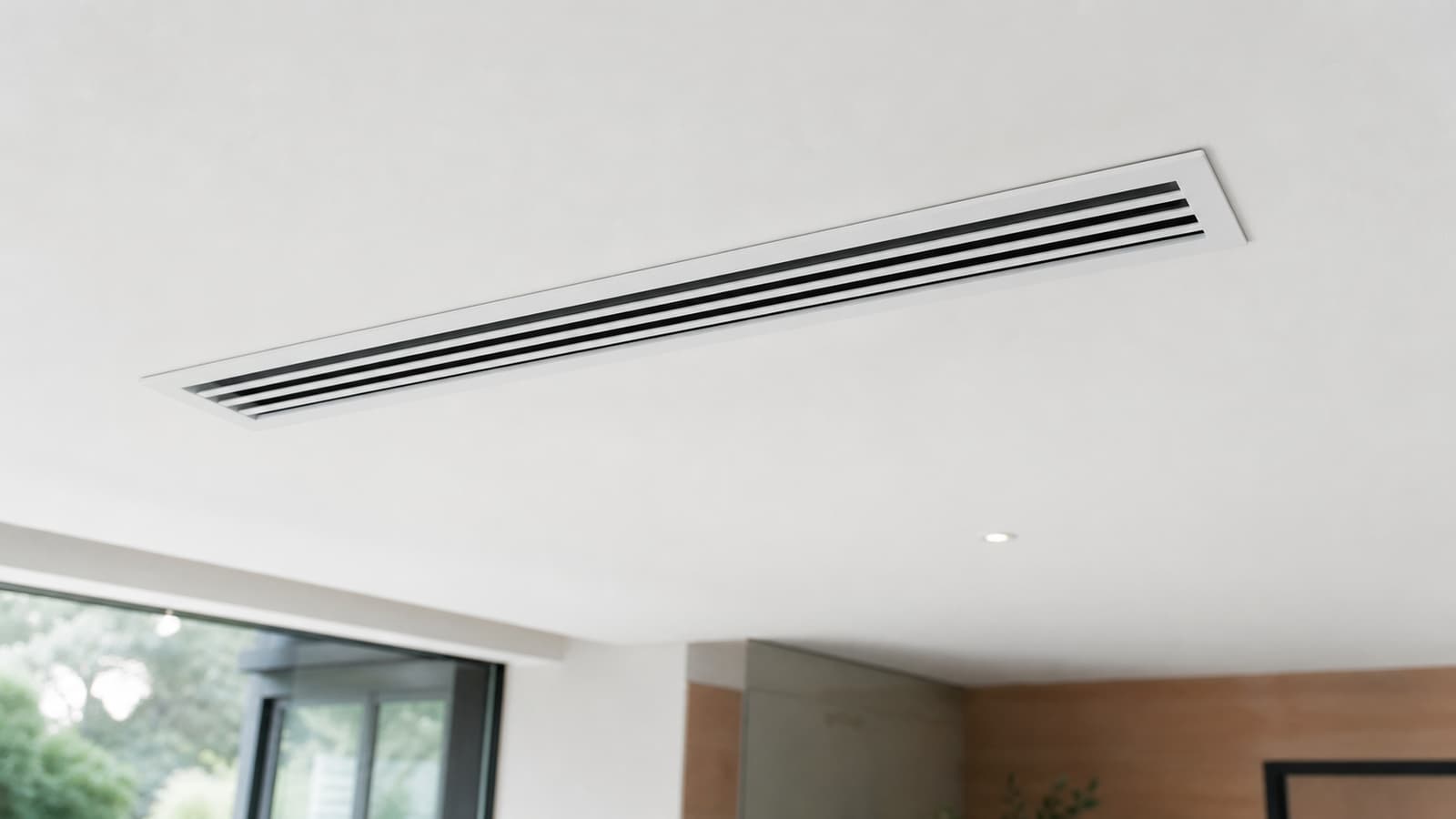 Grille de soufflage gainable intégrée dans un plafond blanc, lumière naturelle